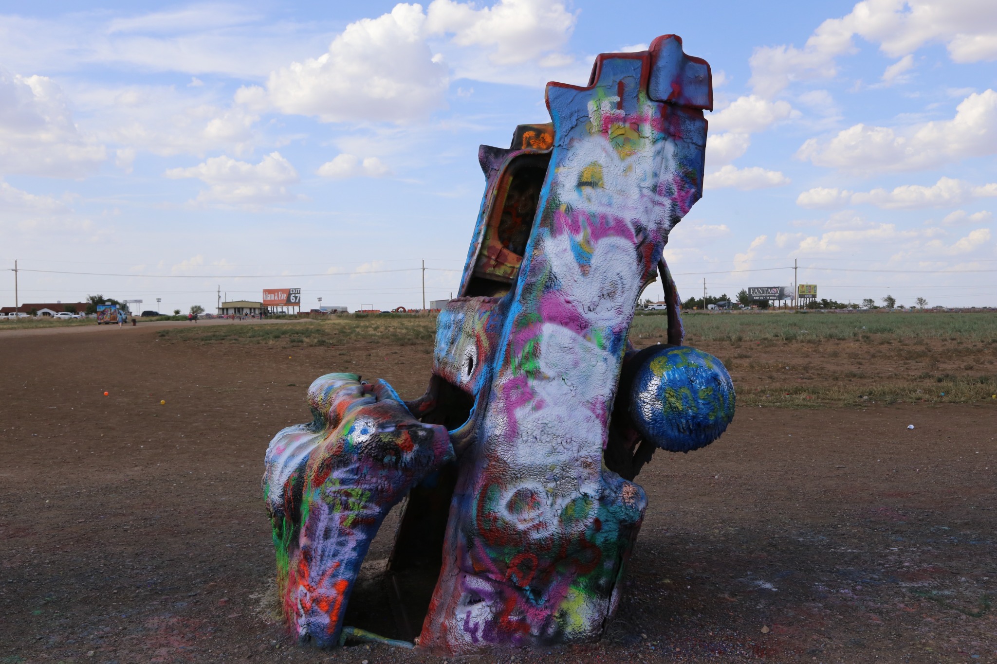 A paint-covered Cadillac standing nose-first in the ground.