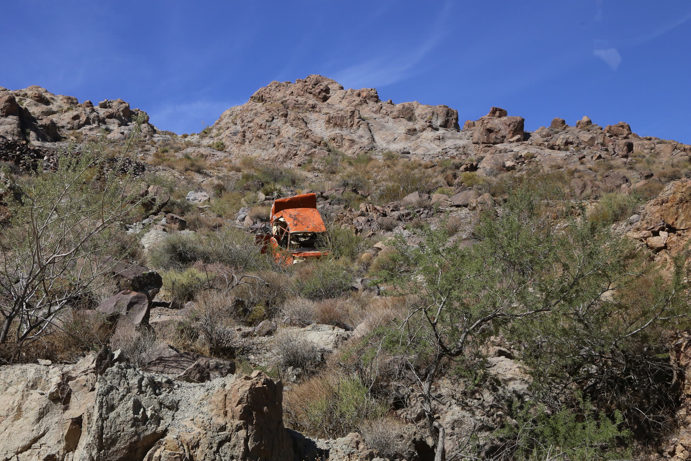 A rusted automobile clings to the rocky hillside along the Sidewinder.